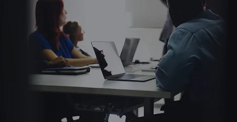 A group sitting at a desk with laptops open and running NordVPN in the background